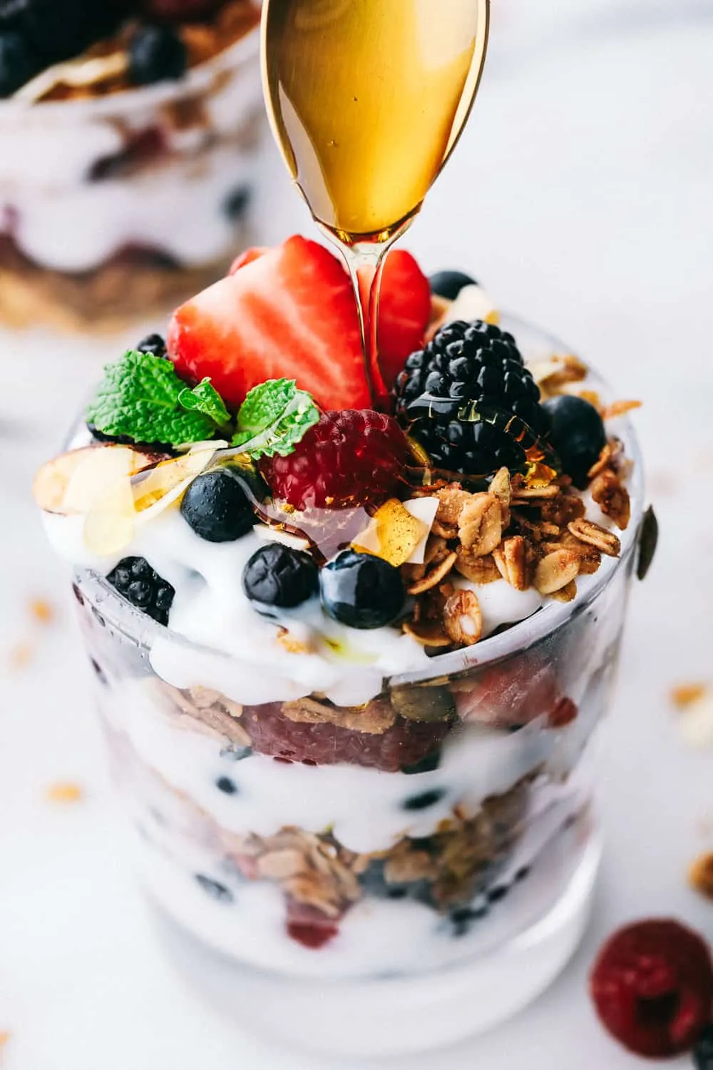 honey, yogurt and berry parfait with granola in glass dish